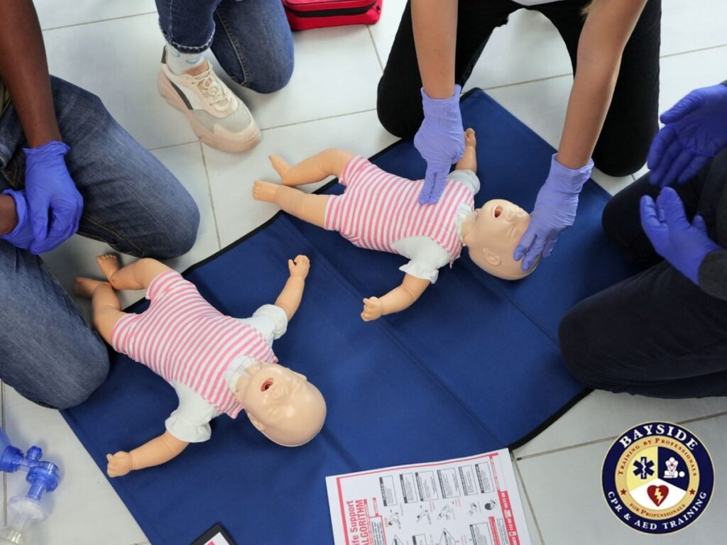 students practicing cpr on two pediatric training manikins